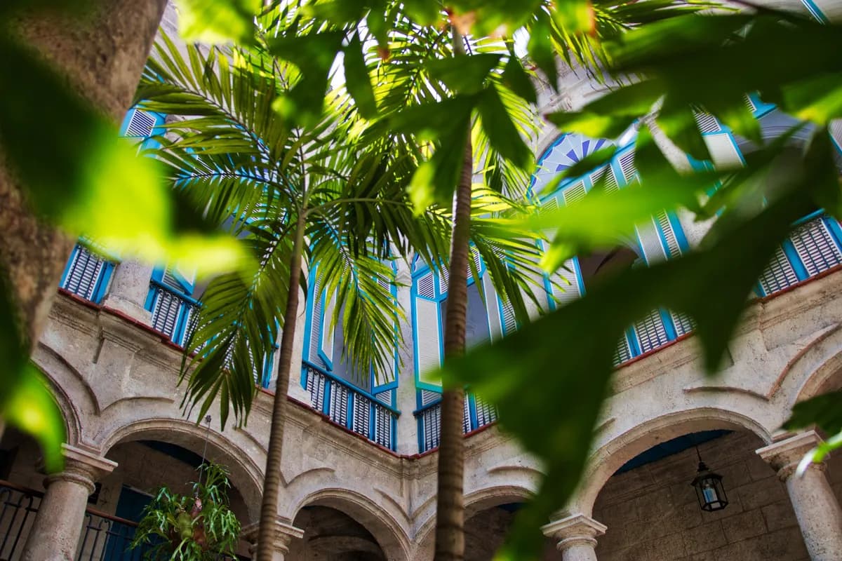 Exemple d'image BookNoFees : cour intérieure tropicale avec des palmiers et des balcons historiques à Cuba