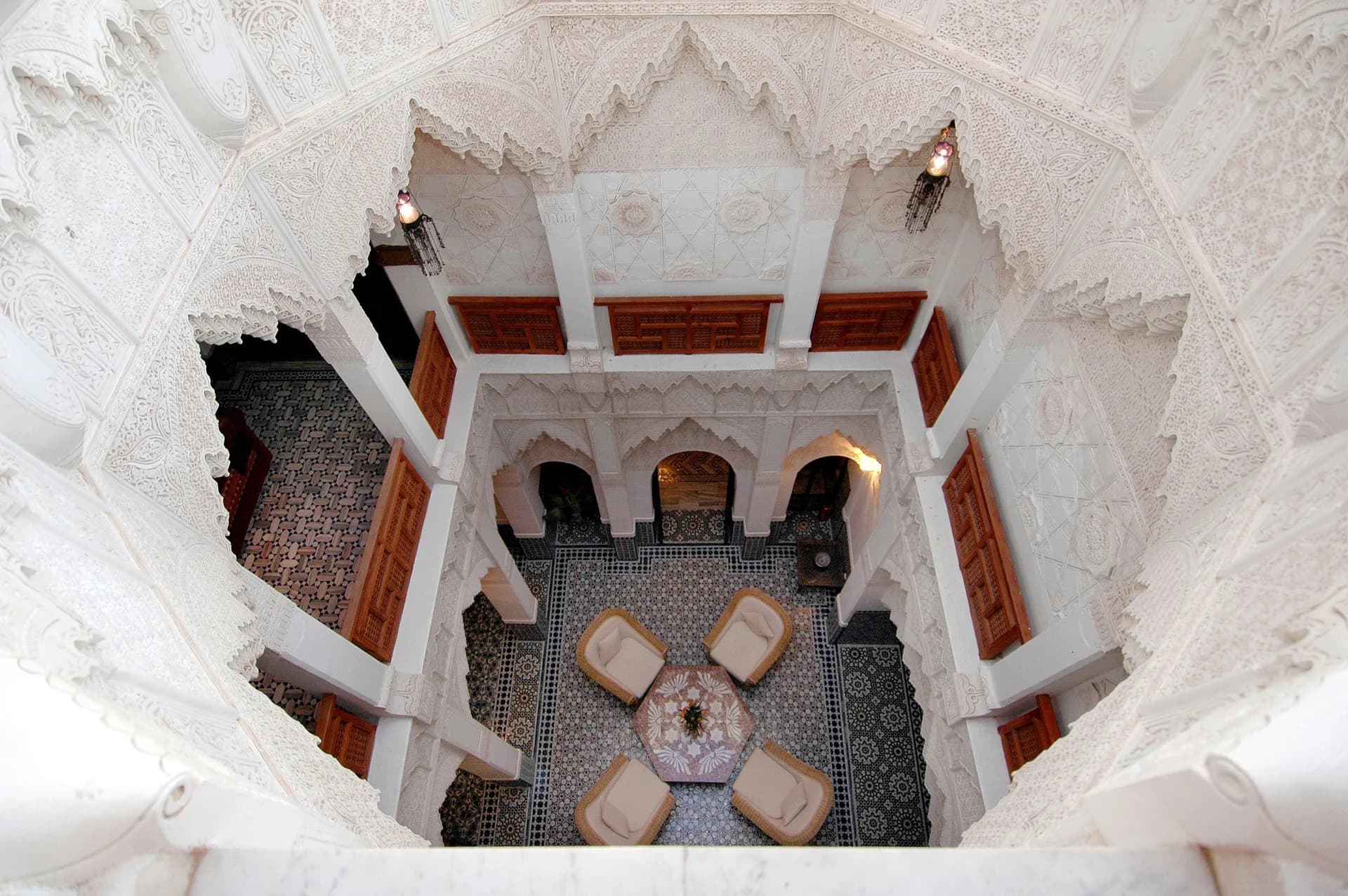 Exemple d'image BookNoFees : vue plongeante sur la cour intérieure d'un riad avec des arcades décorées et des sièges