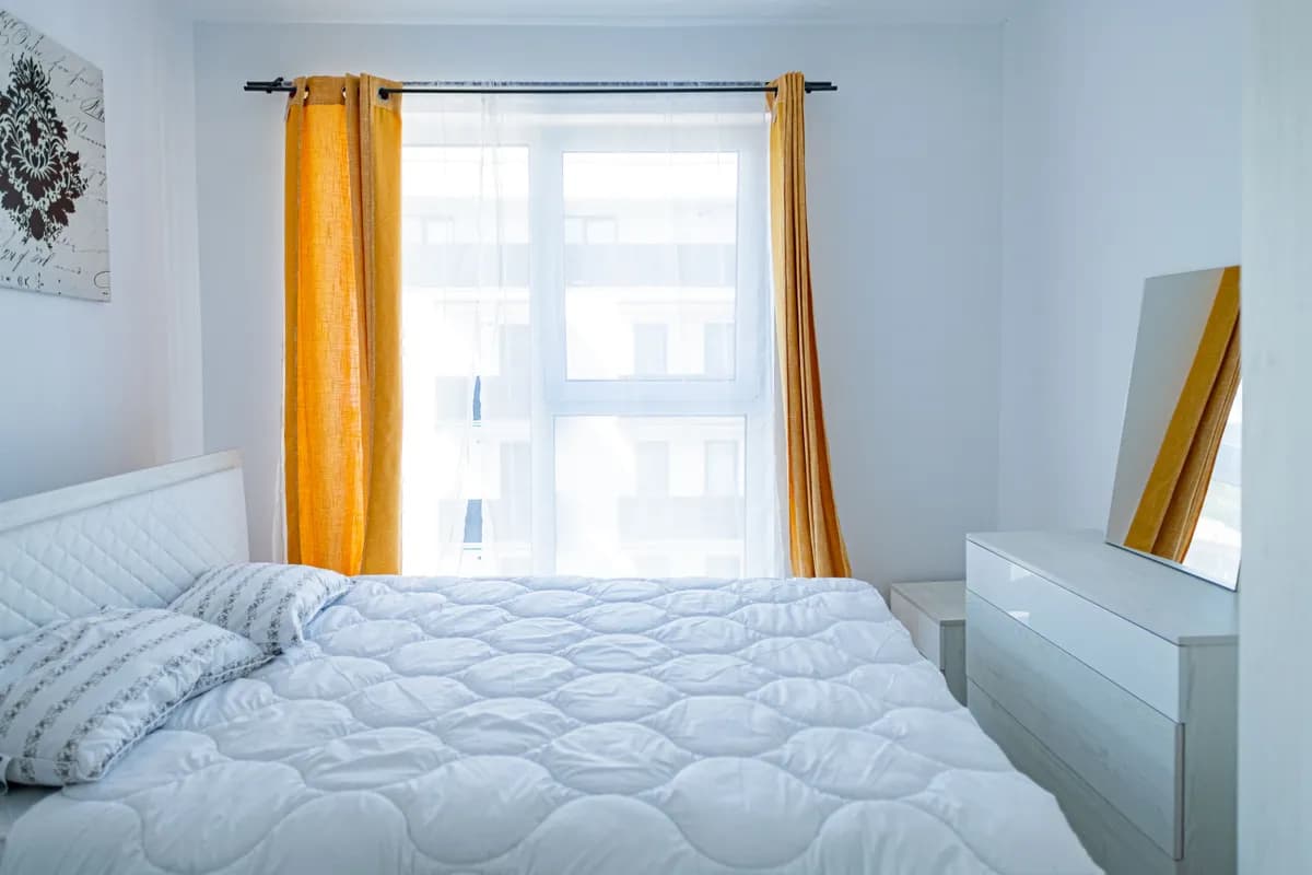 Exemple d'image BookNoFees : chambre avec un lit blanc et des rideaux jaunes