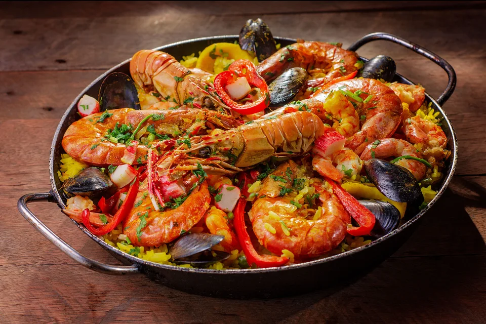 BookNoFees: Photo d’illustration : Une poêlée de paella aux fruits de mer garnie de crustacés et de poivrons rouges