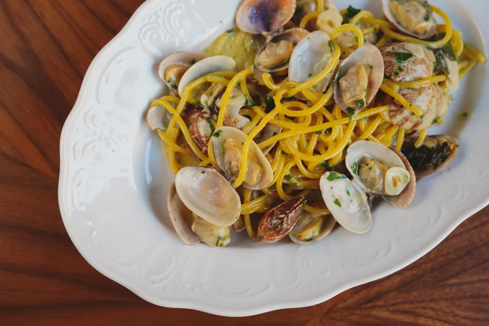 BookNoFees: Photo d’illustration : Spaghettis aux palourdes dans une assiette blanche