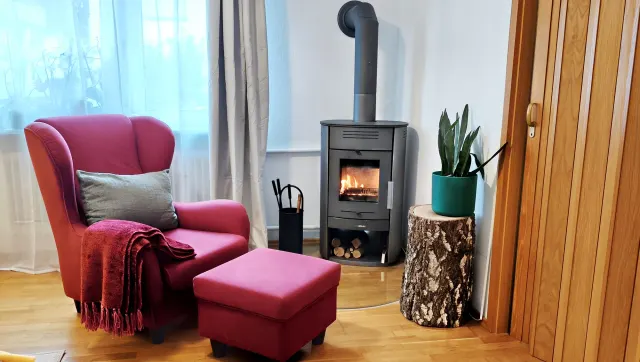 BookNoFees : location de vacances à Bensheim – Salon avec poêle à bois, fauteuil rose et table d'appoint en souche d'arbre