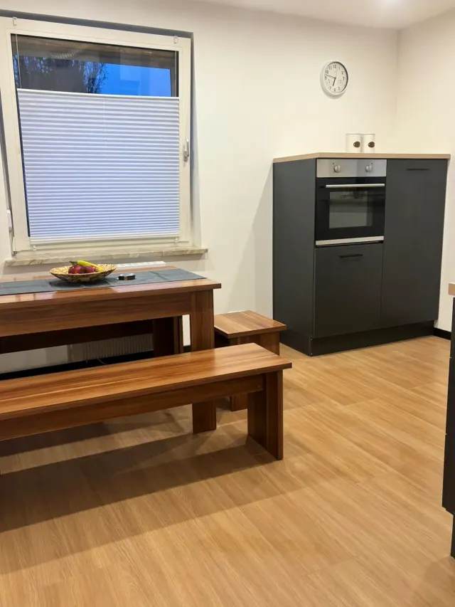 BookNoFees : location de vacances à Bodenwerder – Cuisine avec table à manger en bois, banc, four encastré et fenêtre équipée d'un store