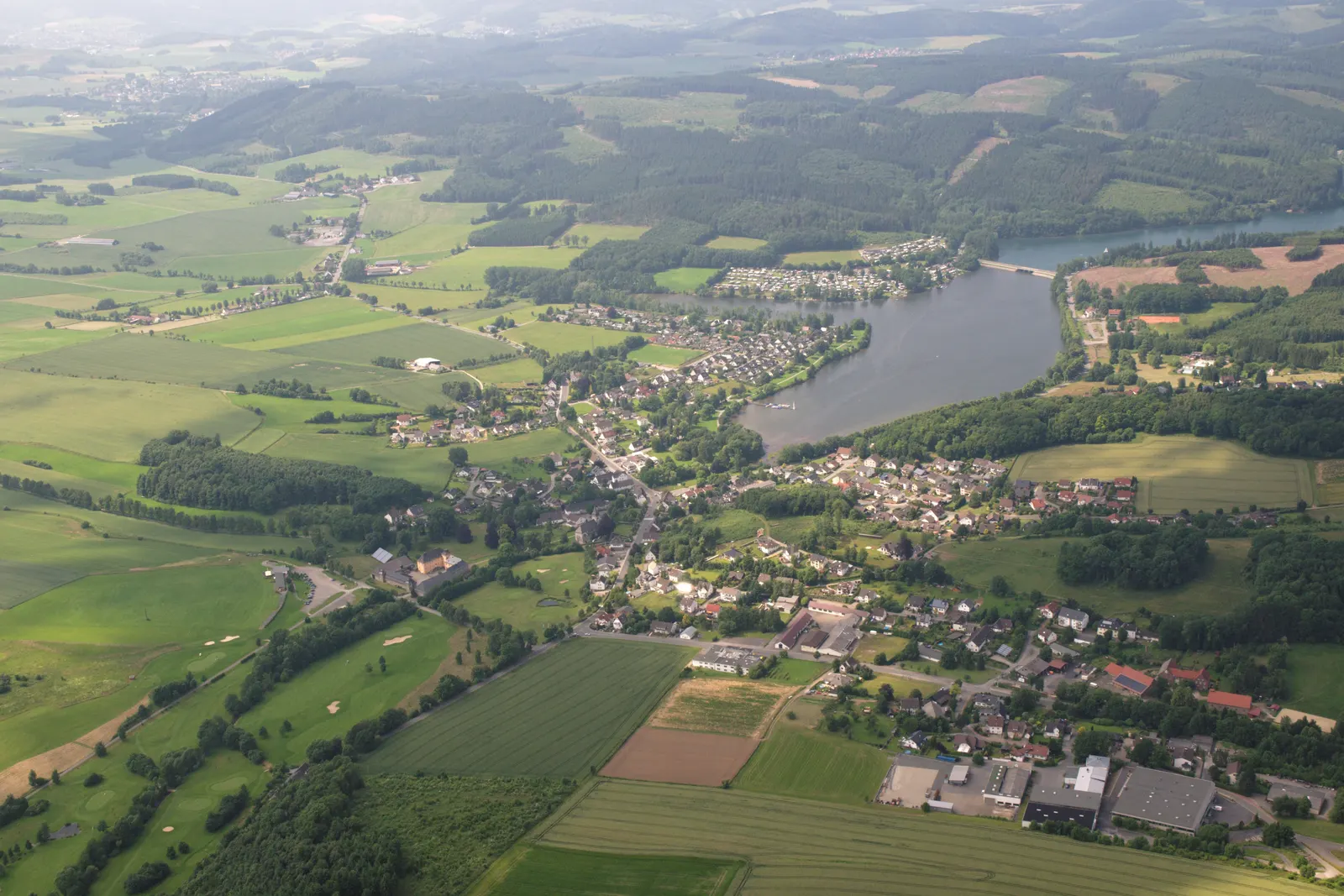 Le lac de Sorpe vu du ciel, avec le village d'Amecke sur sa rive est et les collines boisées du Sauerland qui l'entourent