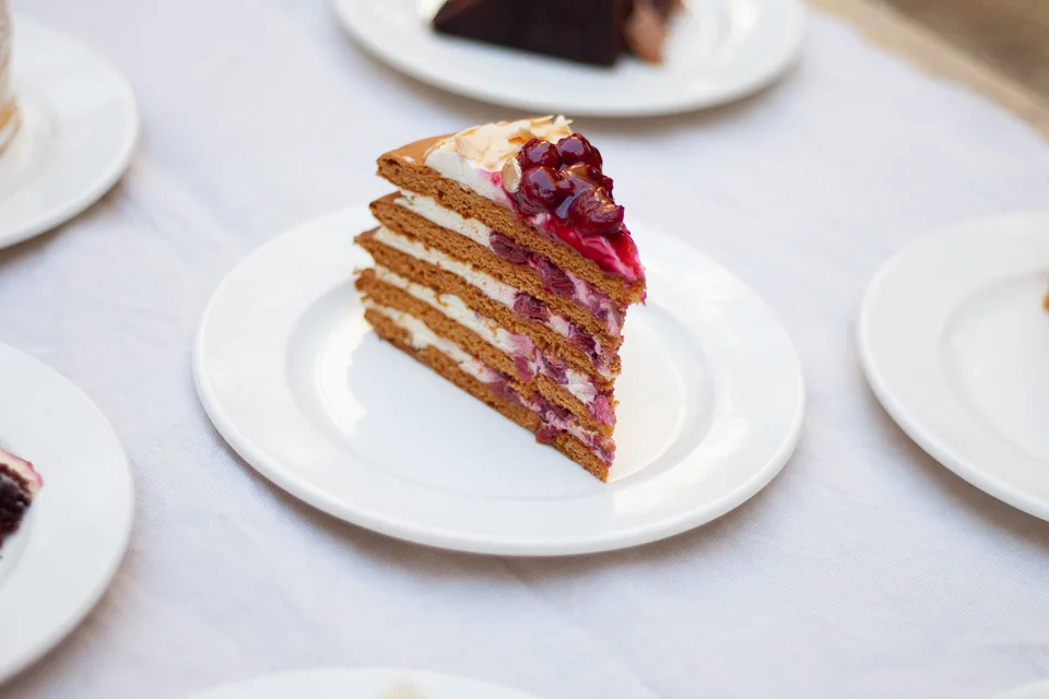 BookNoFees: Photo d’illustration : Une part de gâteau à étages garnie de baies, servie sur une assiette blanche